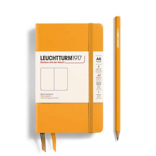 This is a small, warm yellow notebook with an elastic and two bookmarks. The pages are blank other than page numbers in the bottom corners.
